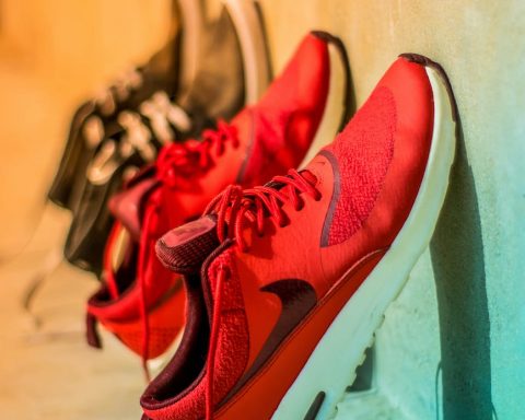 focus photography of pair of red nike running shoes